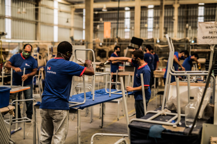 trabalhadores montando cadeiras em fábrica de móveis