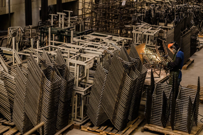 trabalhador realizando solda manual em fábrica de móveis