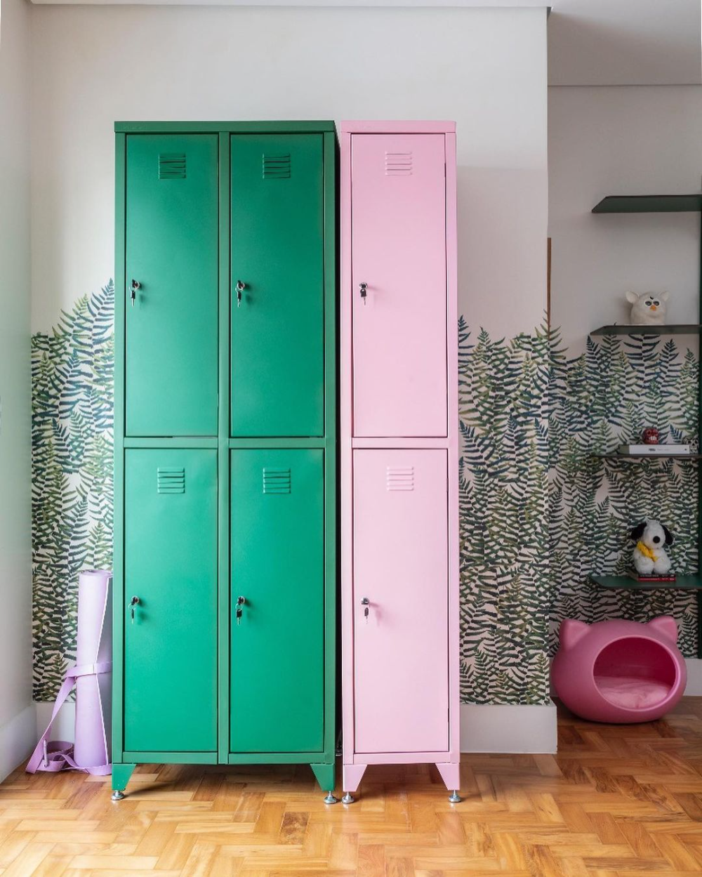 ambiente com lockers de aço verde e rosa e parede com desenho de folhagem
