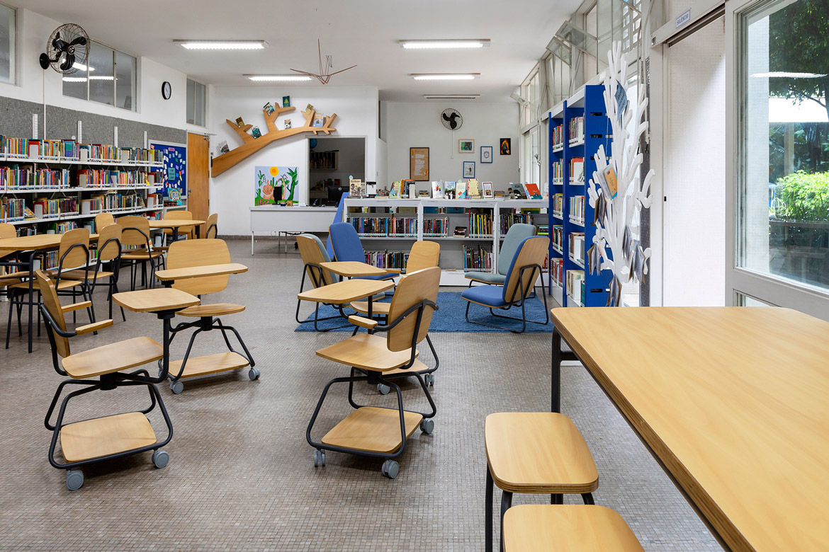sala de atividades em escola com design humanizado. Apresenta cadeiras universitárias com rodízios, poltronas, bancos e mesas escolares.