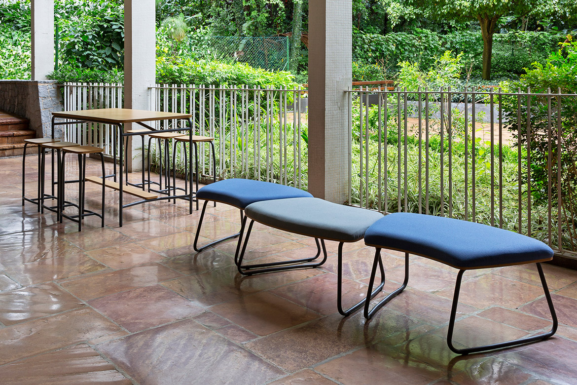design humanizado em área comum de escola em São Paulo, com assentos coletivos e vista para o jardim