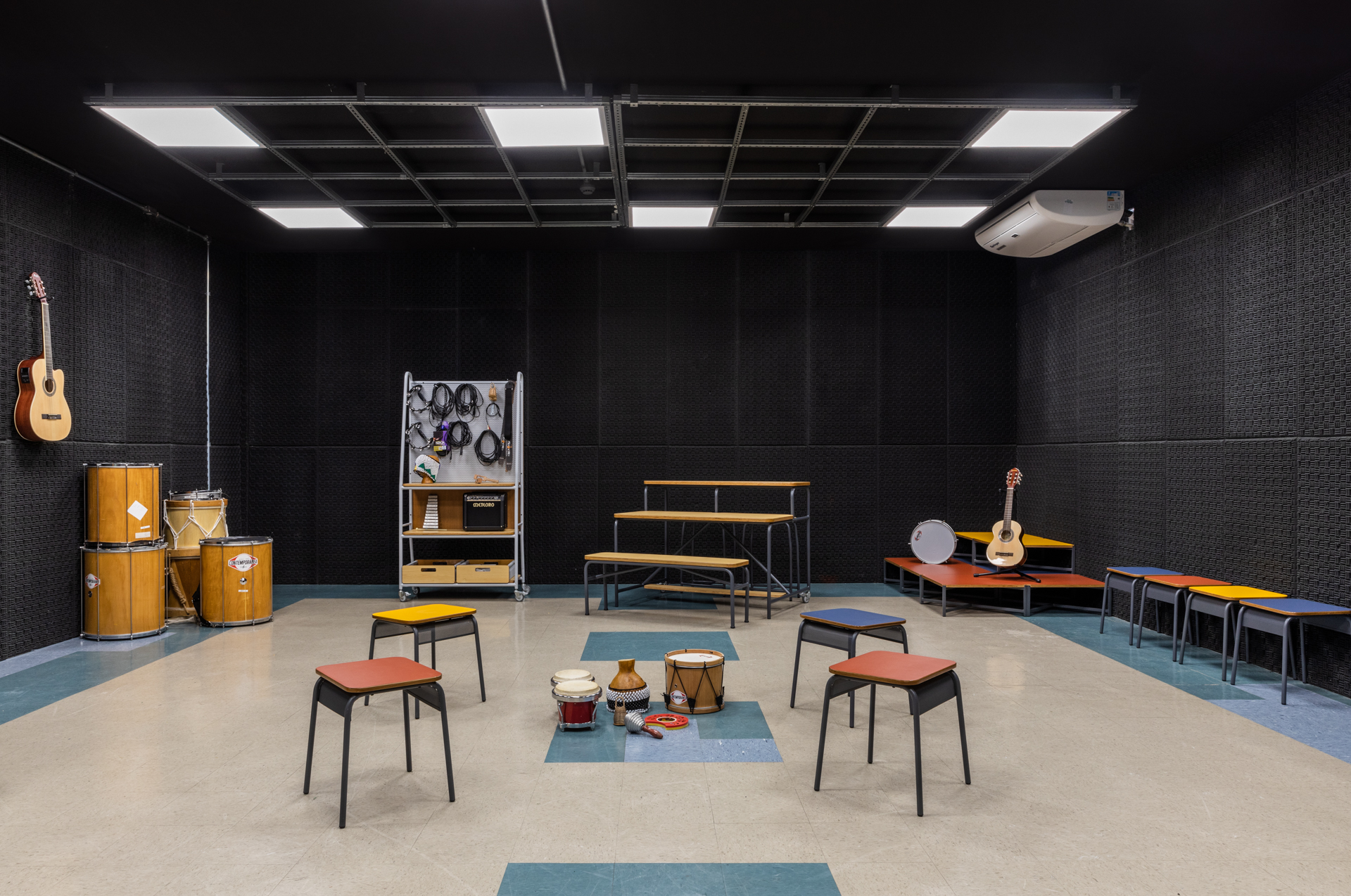 sala de música com paredes revestidas de preto, móveis e instrumentos espalhados pelo local