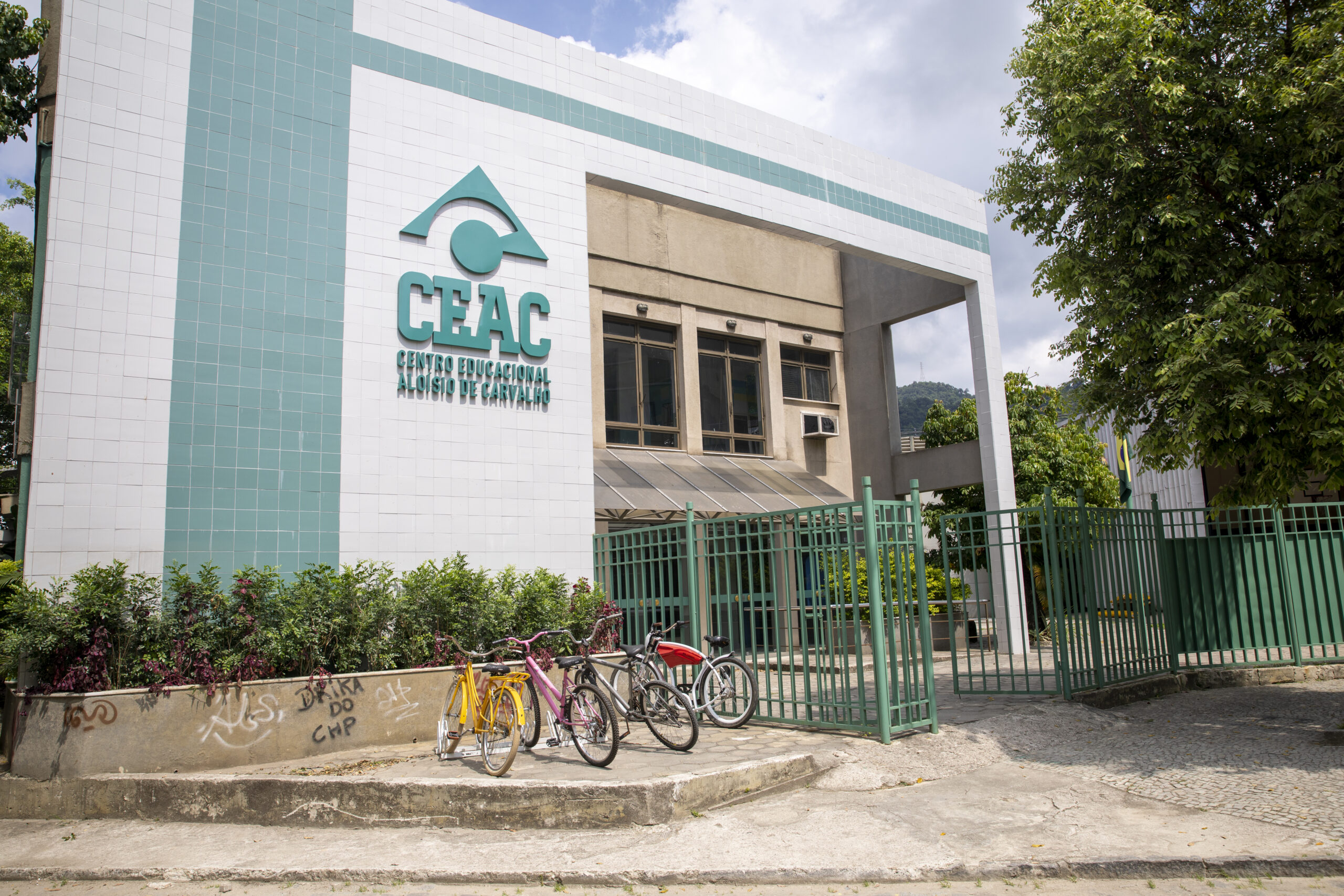 Fachada da escola ficticia Colégio Aloísio de Carvalho, com letreiro e paredes cores branca e verde