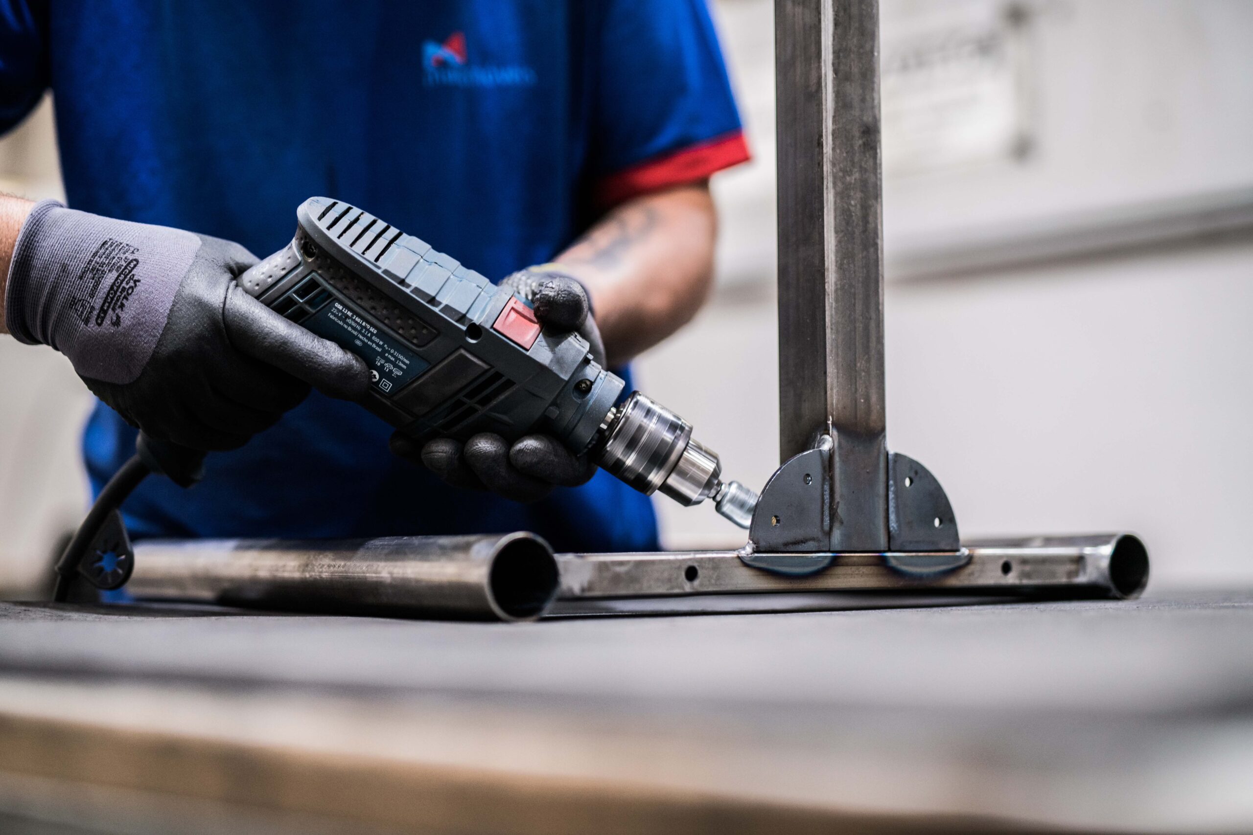 Imagem mostrando um trabalhador utilizando uma furadeira elétrica para fixar metal.