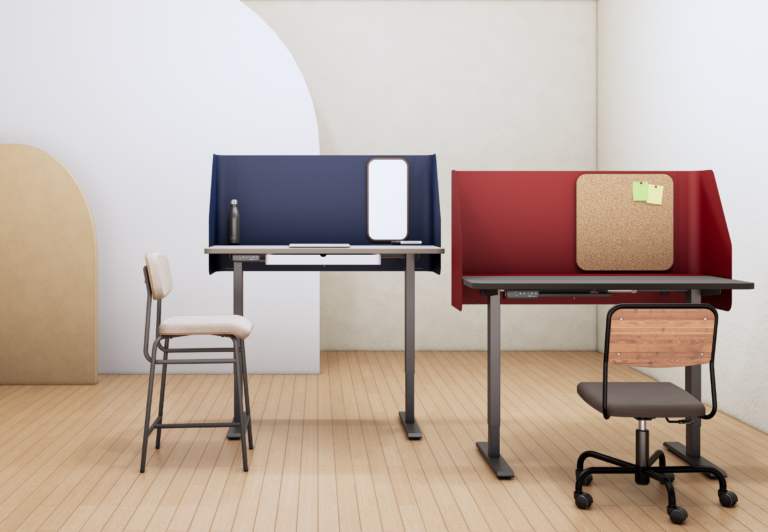Ambiente minimalista com duas mesas com regulagem elétrica de altura, lado a lado, equipadas com divisórias curvas — uma azul e outra vermelha. A mesa azul está acompanhada por uma cadeira alta estofada, enquanto a vermelha tem uma cadeira giratória com encosto de madeira. O espaço é delimitado por painéis decorativos de formas orgânicas em tons neutros.