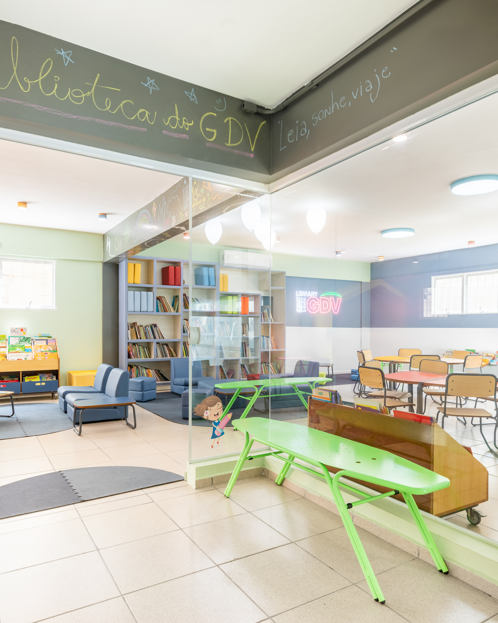 Uma biblioteca escolar colorida com estantes de livros, mesas e sofás, demonstrando a variedade e funcionalidade de móveis escolares.