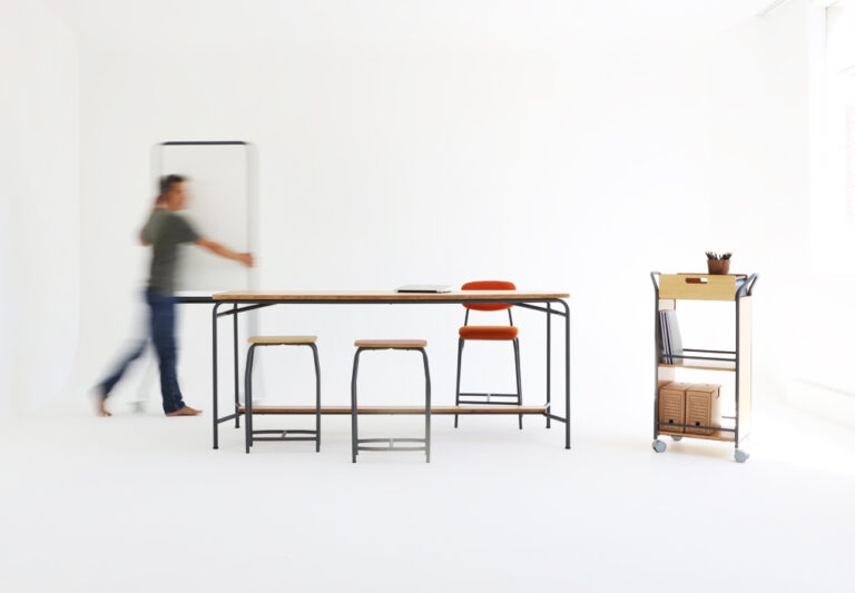 Mesa alta com banquetas e carrinho organizador em estúdio branco, simbolizando a qualidade e padronização da certificação ISO 9001:2015.